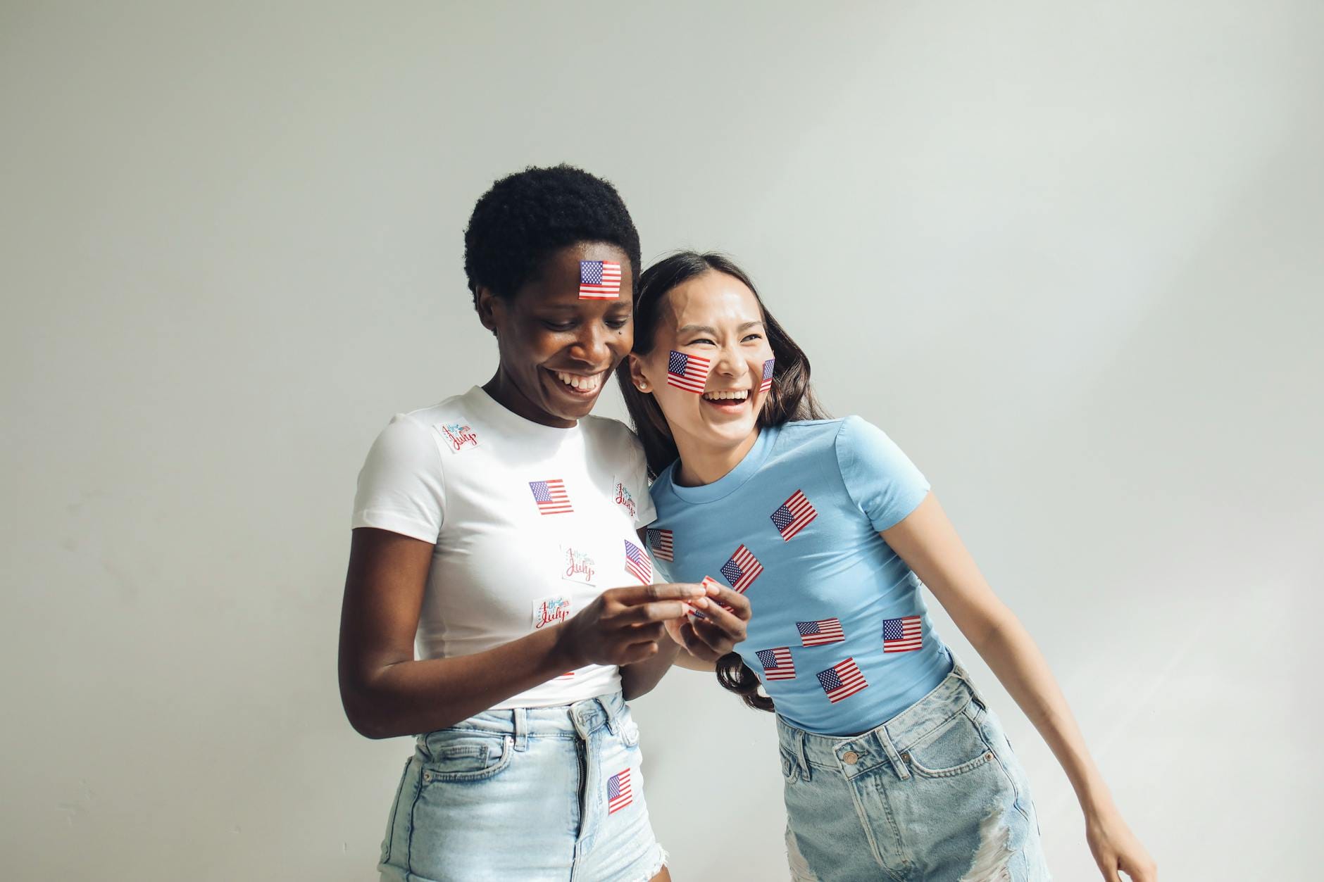 Dwie kobiety w domu świętują z flagami USA, ubrane w patriotyczne stroje