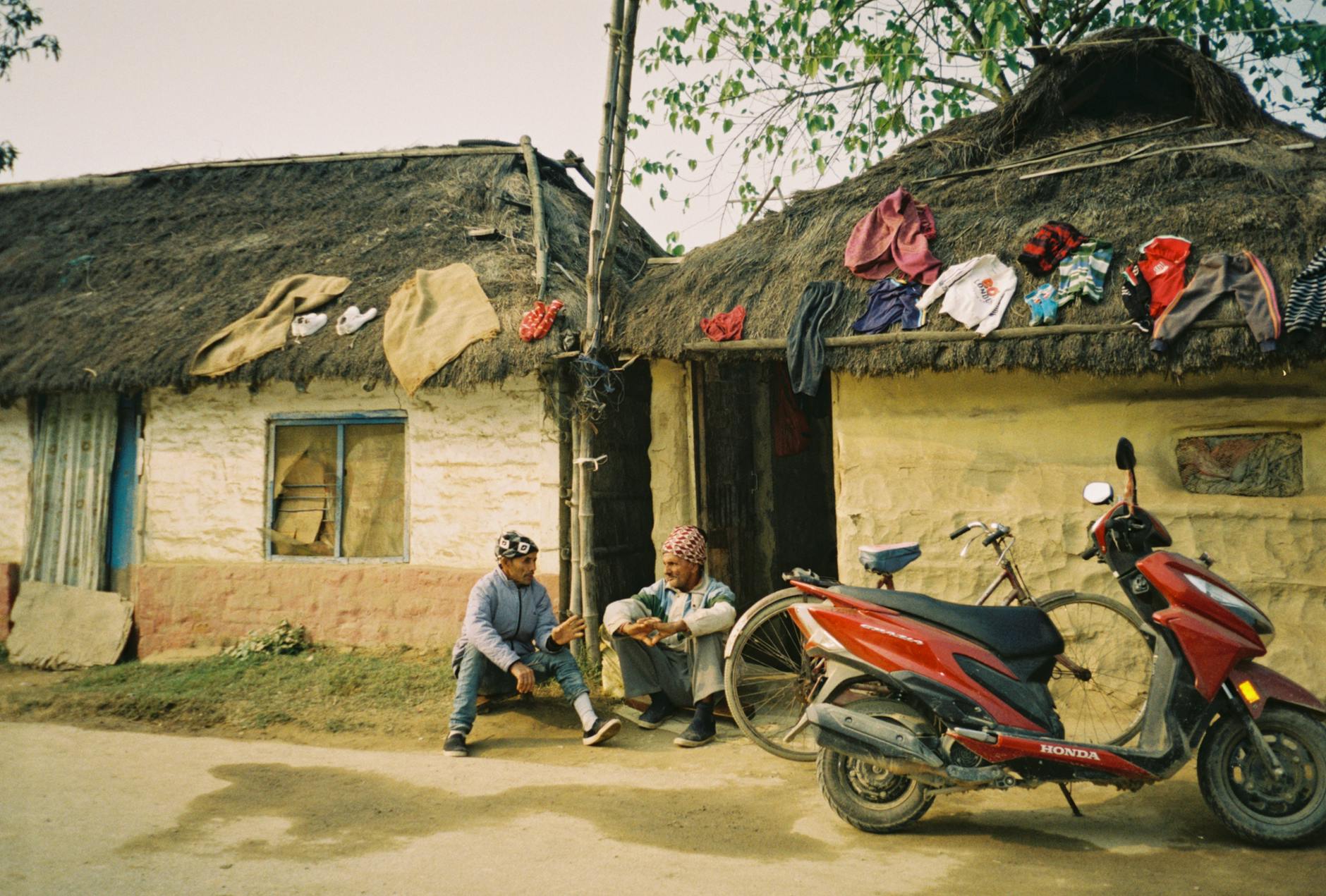 Dwóch mężczyzn rozmawia przed tradycyjnym domem w Brazylii obok motocykla