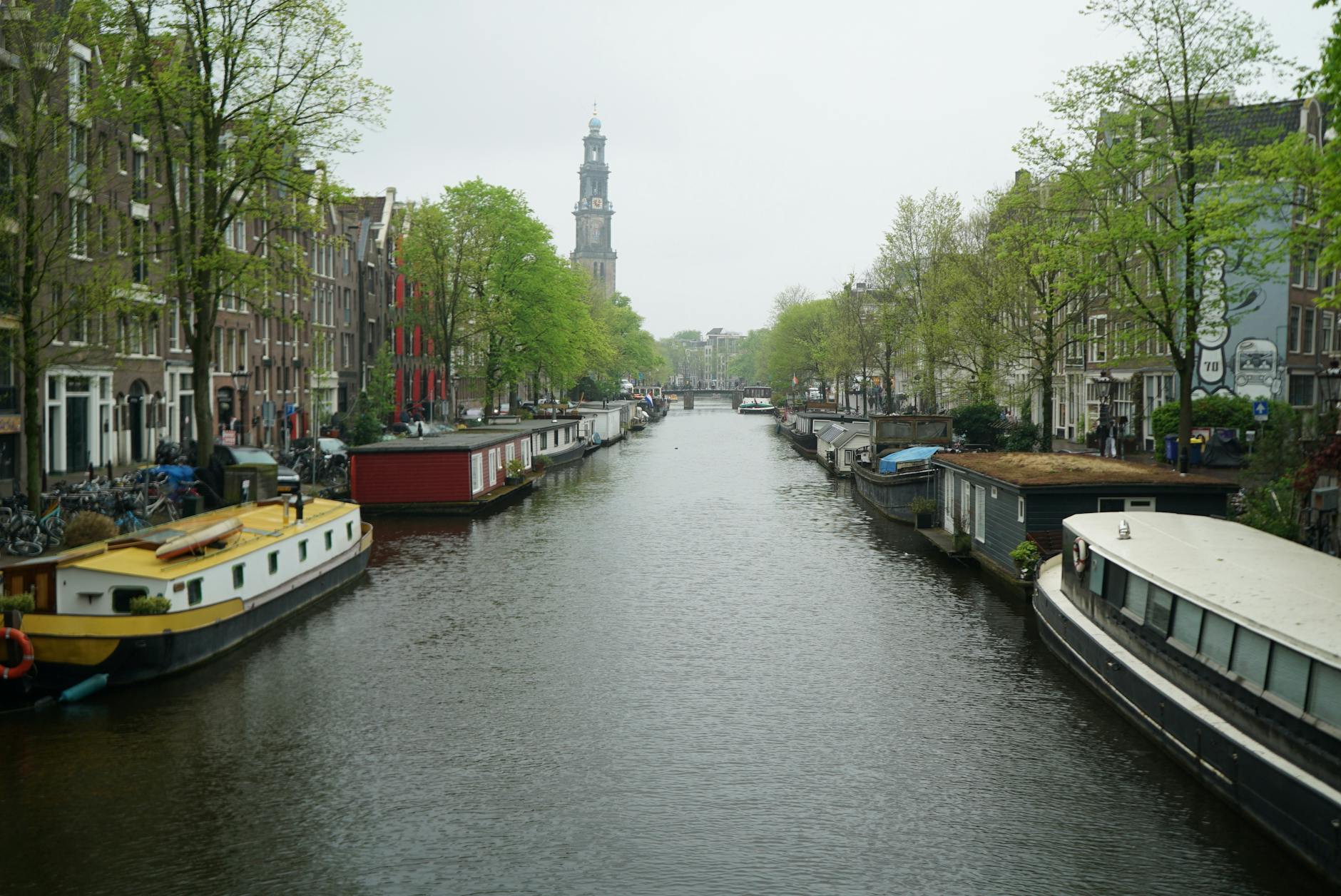 Spokojny poranek nad kanałem w Amsterdamie z barkami mieszkalnymi