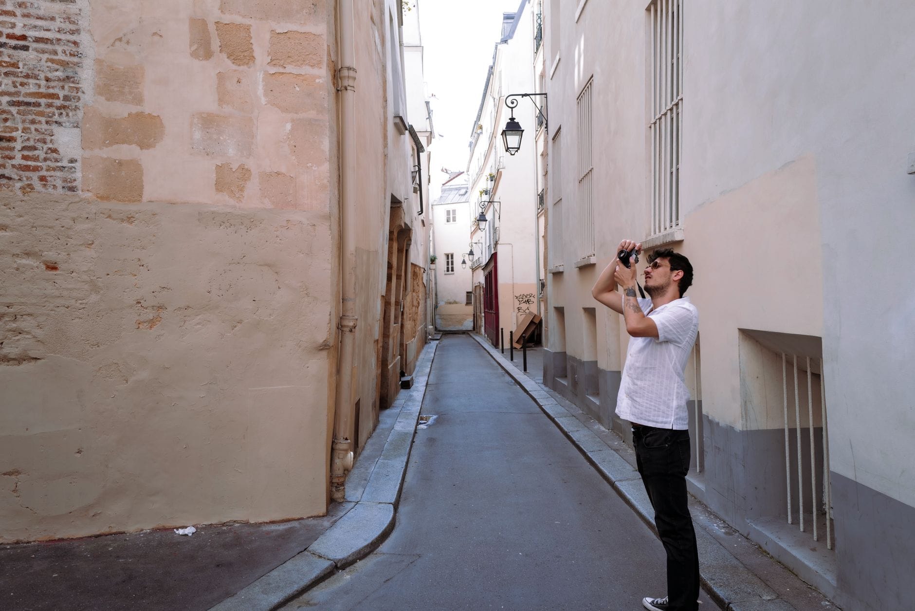 Z aparatem po Lwowie: najlepsze trasy fotograficzne poza pocztówkowymi ujęciami Fotografujący mężczyzna w wąskiej uliczce starego miasta we Lwowie