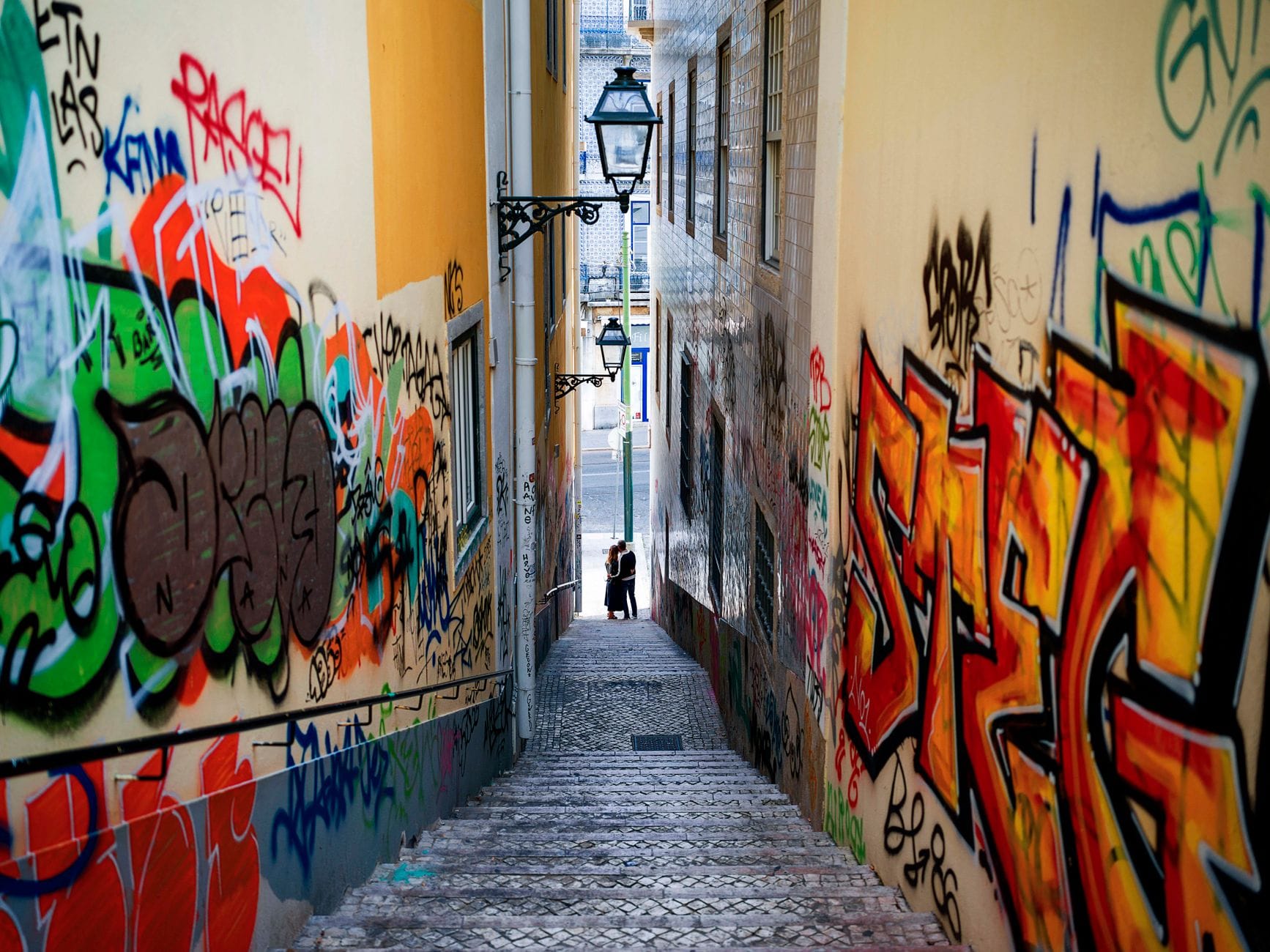 Kolorowe graffiti w wąskiej lizbońskiej uliczce poza turystycznym szlakiem