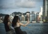 Niezbędne aplikacje na telefon w Hongkongu: transport, płatności, mapy i zamawianie jedzenia Dwie kobiety robią selfie przy porcie i panoramie Hongkongu