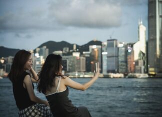 Niezbędne aplikacje na telefon w Hongkongu: transport, płatności, mapy i zamawianie jedzenia Dwie kobiety robią selfie przy porcie i panoramie Hongkongu